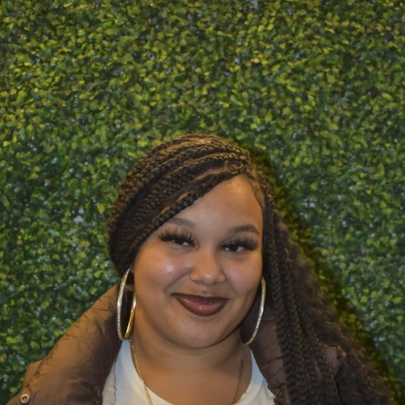 Chavely with long braids and a brown puffer vest