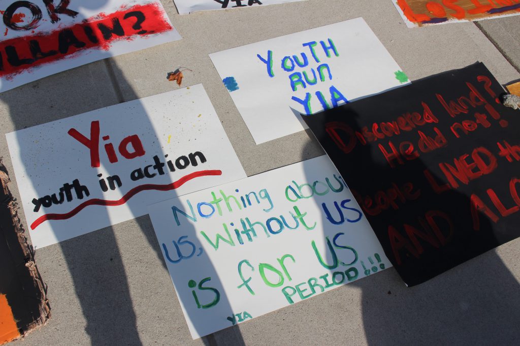 hand-made posters lying on the sidewalk. one of them reads "Nothing about us without us is for us PERIOD!!!"