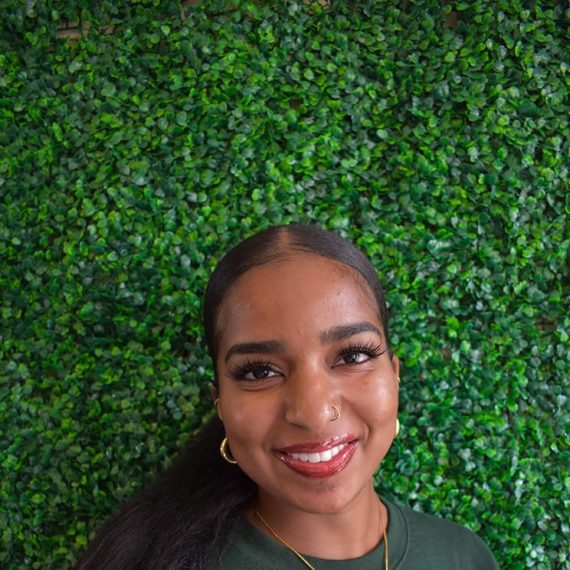 Aisha with a big smile and a pendant necklace with an 'A' on it.